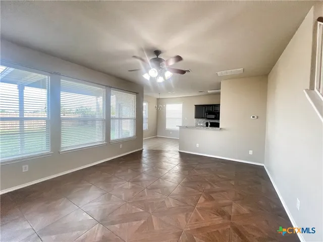 a view of an empty room with a window and a kitchen