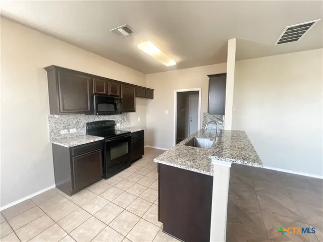 a large kitchen with kitchen island granite countertop a sink and stainless steel appliances