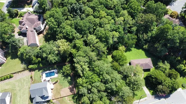 an aerial view of residential house with outdoor space and trees all around