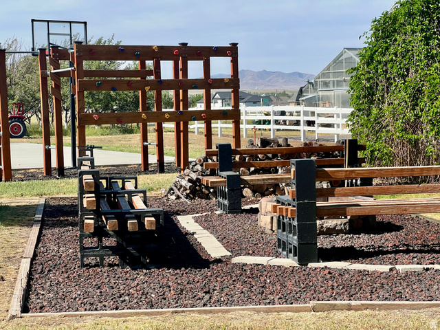 812 East Bates Cyn Road Tooele, UT 84074 - Photo 96 of 144 Outdoor recreational area featuring a wooden climbing structure with colorful holds, a basketball hoop, and two dark-toned metal and wood benches