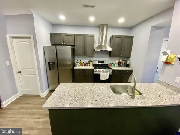 a kitchen with granite countertop a refrigerator a stove a sink a oven with wooden floor