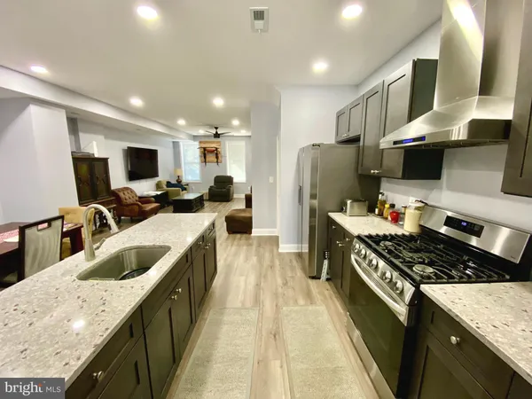 a kitchen with kitchen island granite countertop a sink a counter top space stainless steel appliances and cabinets