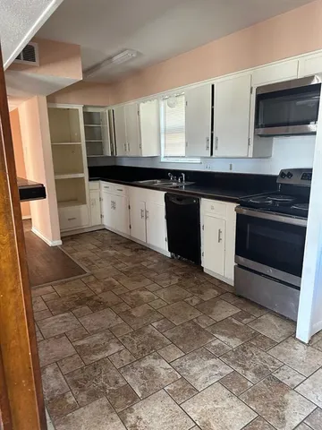 a kitchen with granite countertop a stove a sink and a microwave
