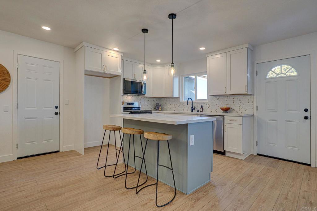 4205 Rene Drive San Diego, CA 92154 - Photo 10 of 29 a kitchen with kitchen island granite countertop wooden floors refrigerator and cabinets