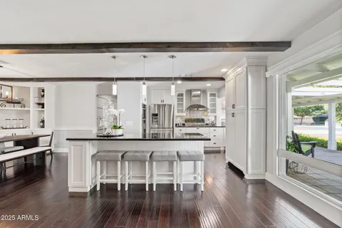 a kitchen with granite countertop a refrigerator a sink and white cabinets