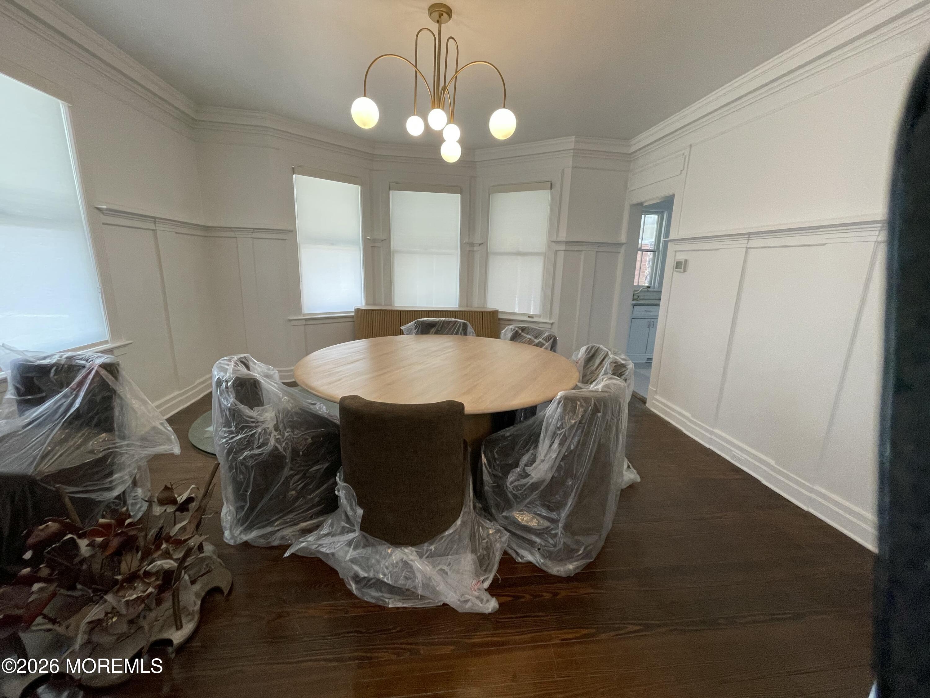211 Cedar Avenue Allenhurst, NJ 07711 - Photo 4 of 20 a dining room with wooden floor a chandelier a wooden table and chairs