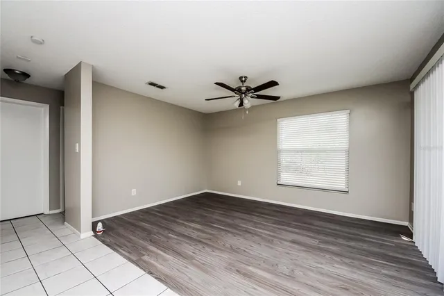 a view of an empty room with a window and wooden floor