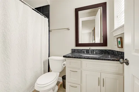 a bathroom with a granite countertop sink vanity mirror and toilet