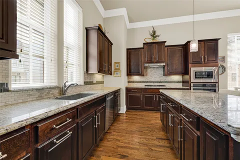 a kitchen with stainless steel appliances granite countertop a sink wooden cabinets and a granite counter tops