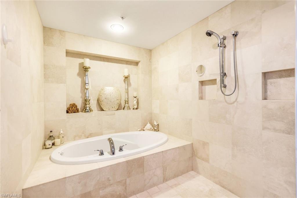 275 Indies Way, Unit 605 Naples, FL 34110 - Photo 18 of 41 Bathroom with tile walls and a relaxing tiled bath