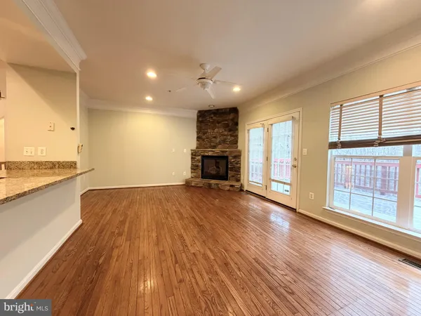 an empty room with wooden floor a fireplace and windows