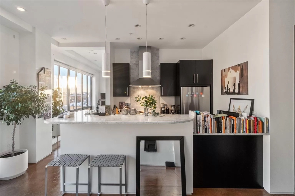 a kitchen with kitchen island granite countertop a refrigerator and a view of living room