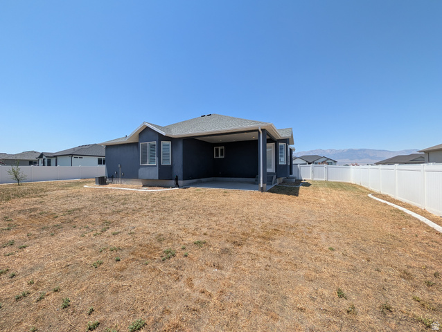 171 South Mustang Road East Grantsville, UT 84029 - Photo 41 of 41 Exterior rear of the property featuring a covered patio, a privacy fence, and a mountain range backdrop