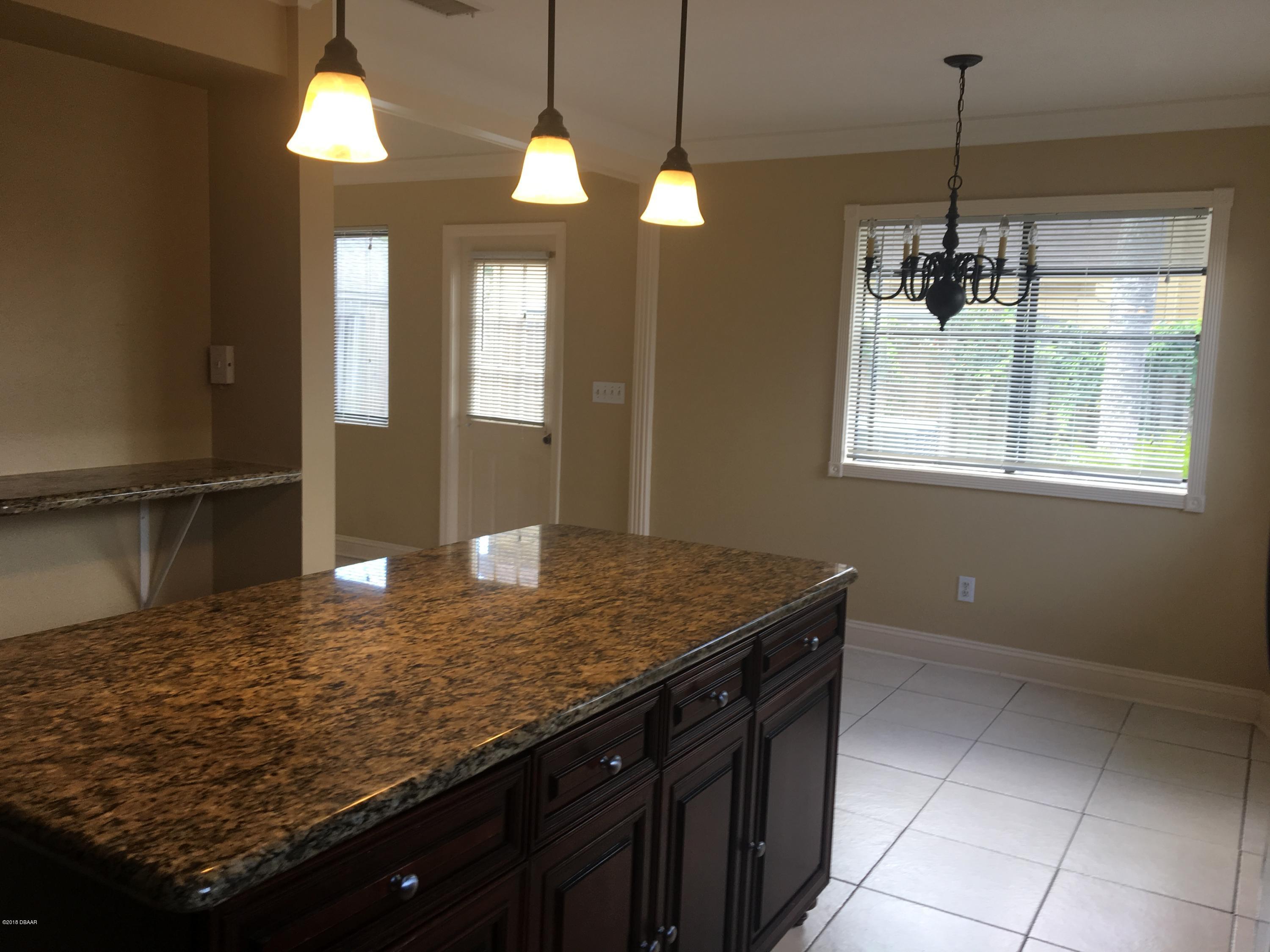 132 Tern Court Daytona Beach, FL 32119 - Photo 8 of 34 a kitchen with kitchen island granite countertop a stove a sink a refrigerator dining table and chairs
