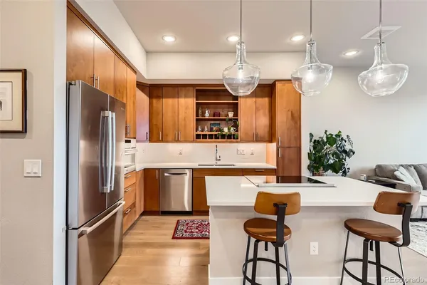 a kitchen with granite countertop a refrigerator oven a sink dishwasher a dining table and chairs cabinets with wooden floor