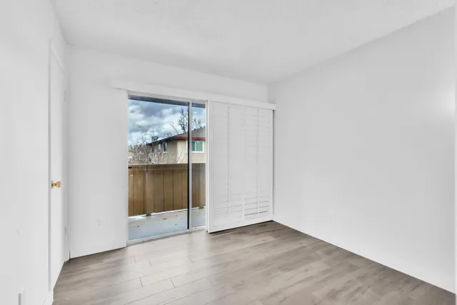 a view of an empty room with wooden floor and closet