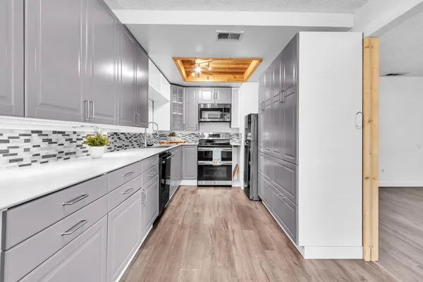 a kitchen with cabinets stainless steel appliances and wooden floor