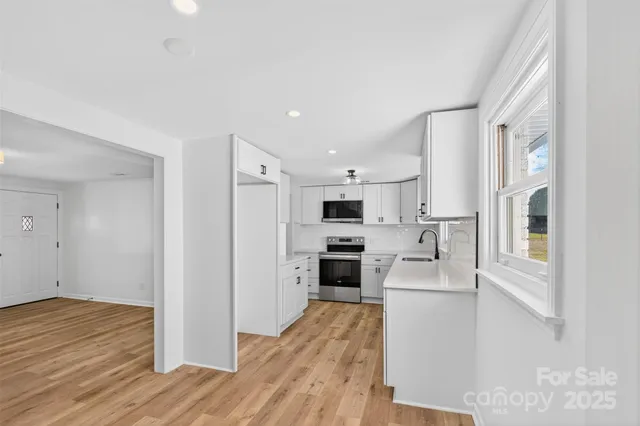 a kitchen with stainless steel appliances granite countertop a refrigerator a stove top oven a sink and dishwasher with wooden floor