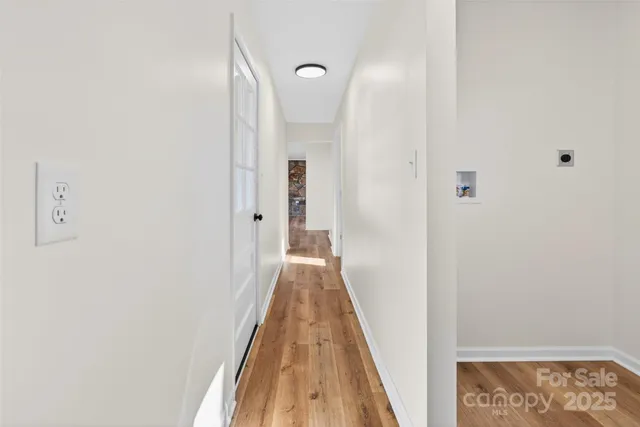 a view of a hallway with wooden floor and a bathroom