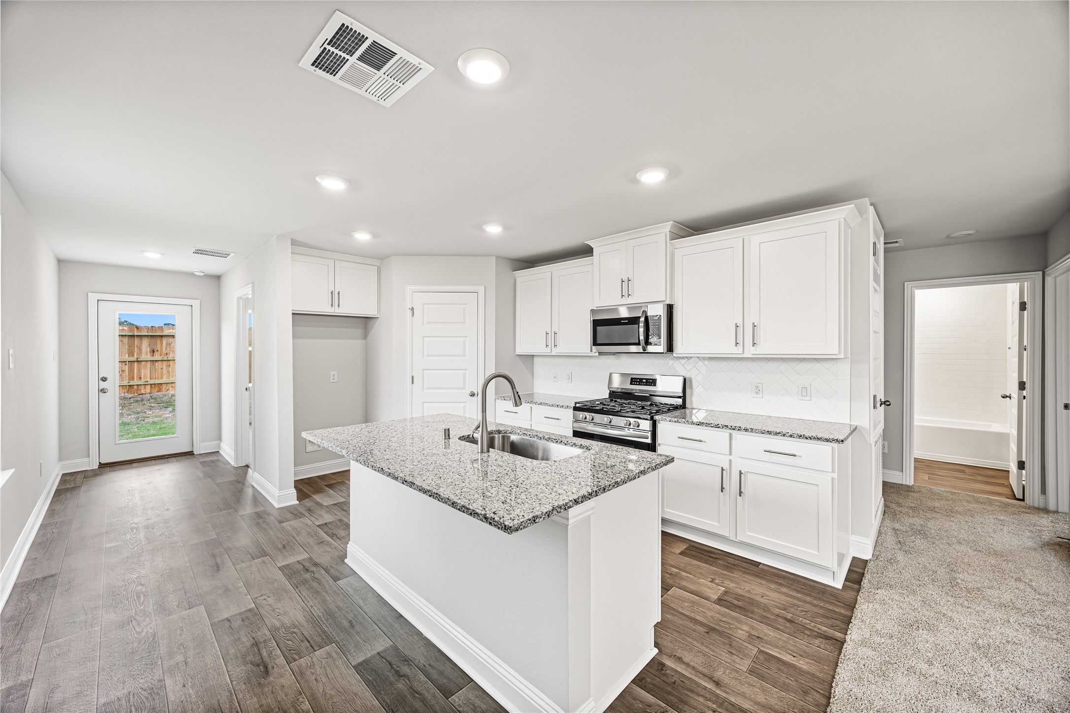 9476 Hard Rock Road Conroe, TX 77303 - Photo 5 of 13 a kitchen with white cabinets and stainless steel appliances