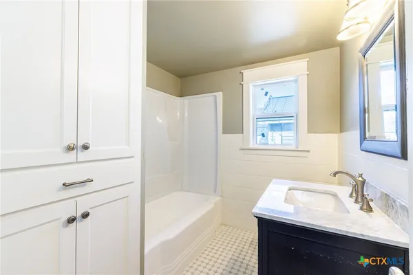 a bathroom with a bathtub sink vanity and mirror