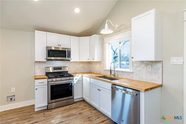 a kitchen with stainless steel appliances a stove sink microwave and cabinets