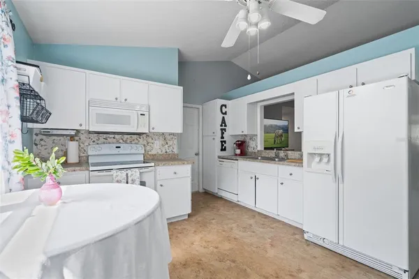 a kitchen with stainless steel appliances a white refrigerator a sink dishwasher a stove and white cabinets