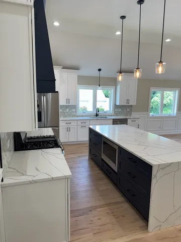 a large kitchen with stainless steel appliances granite countertop a sink a stove and a wooden floors