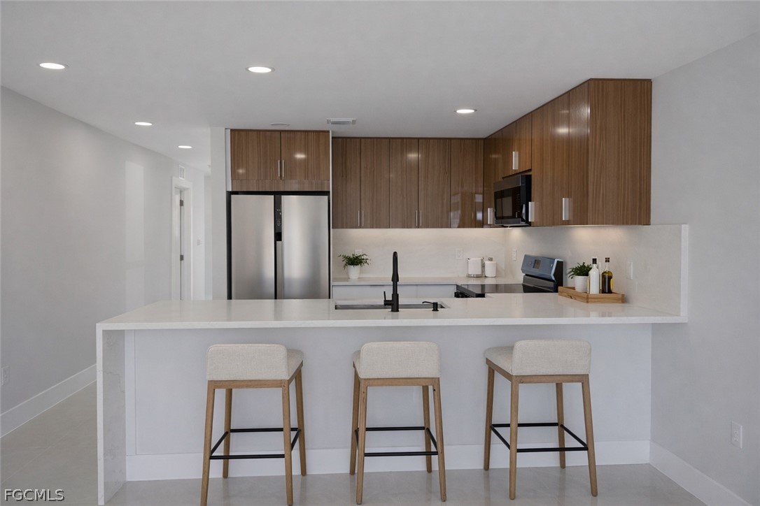 4529 18th Street Southwest Lehigh Acres, FL 33973 - Photo 5 of 50 a kitchen with stainless steel appliances granite countertop a sink a stove a refrigerator with white cabinets and chairs
