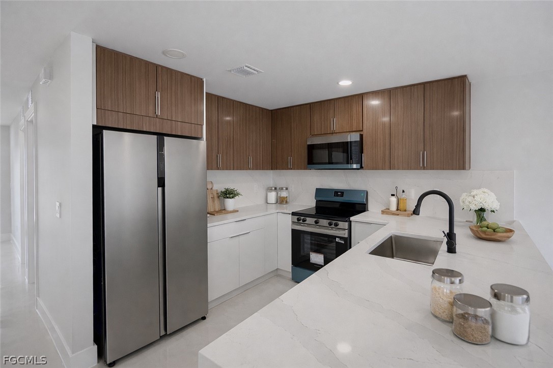 4529 18th Street Southwest Lehigh Acres, FL 33973 - Photo 7 of 50 a kitchen with stainless steel appliances granite countertop a refrigerator a sink a stove a microwave and cabinets