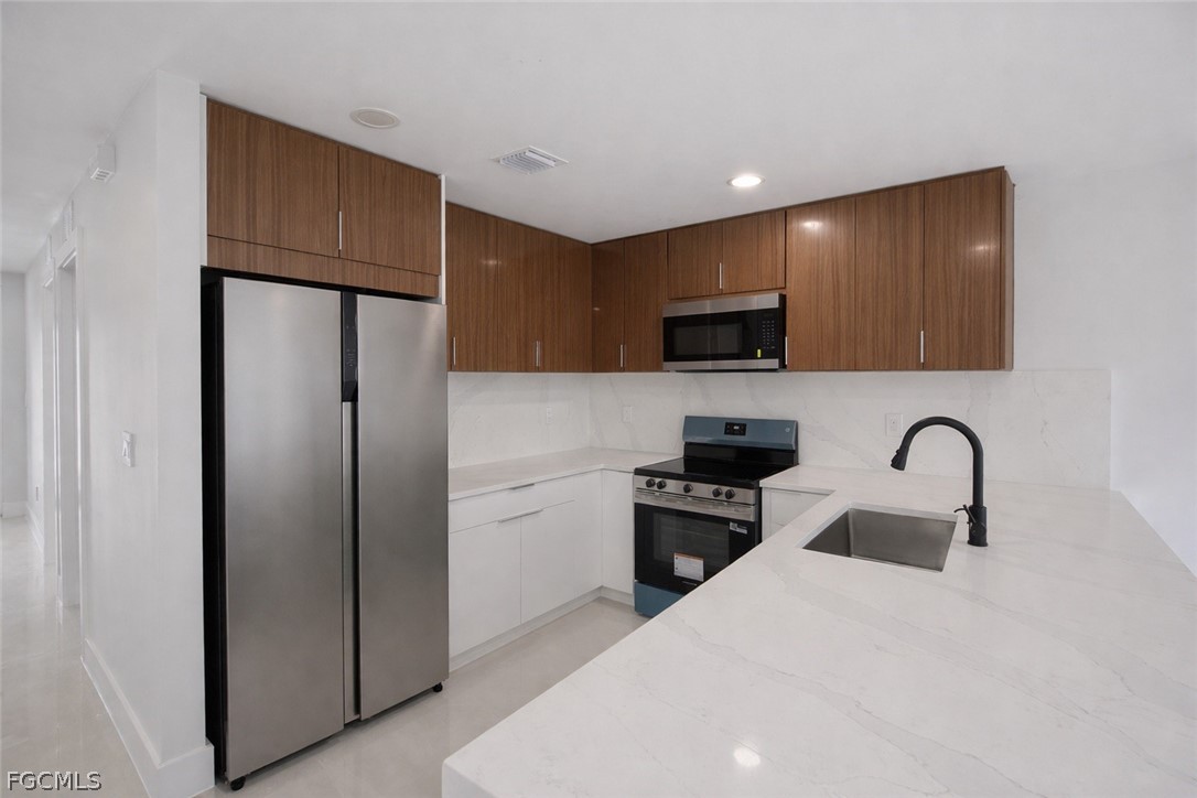 4529 18th Street Southwest Lehigh Acres, FL 33973 - Photo 8 of 50 a kitchen with stainless steel appliances a refrigerator a sink a stove top oven and a refrigerator