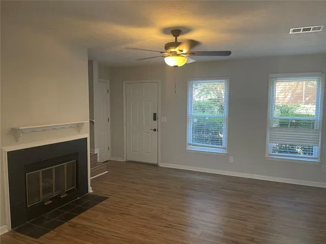 a view of an empty room with wooden floor fireplace and a window