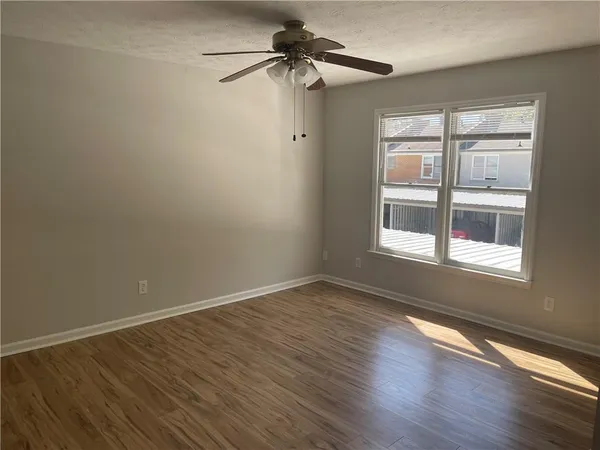 a view of an empty room with wooden floor and a window