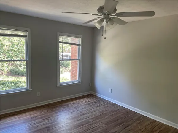 an empty room with wooden floor fan and windows