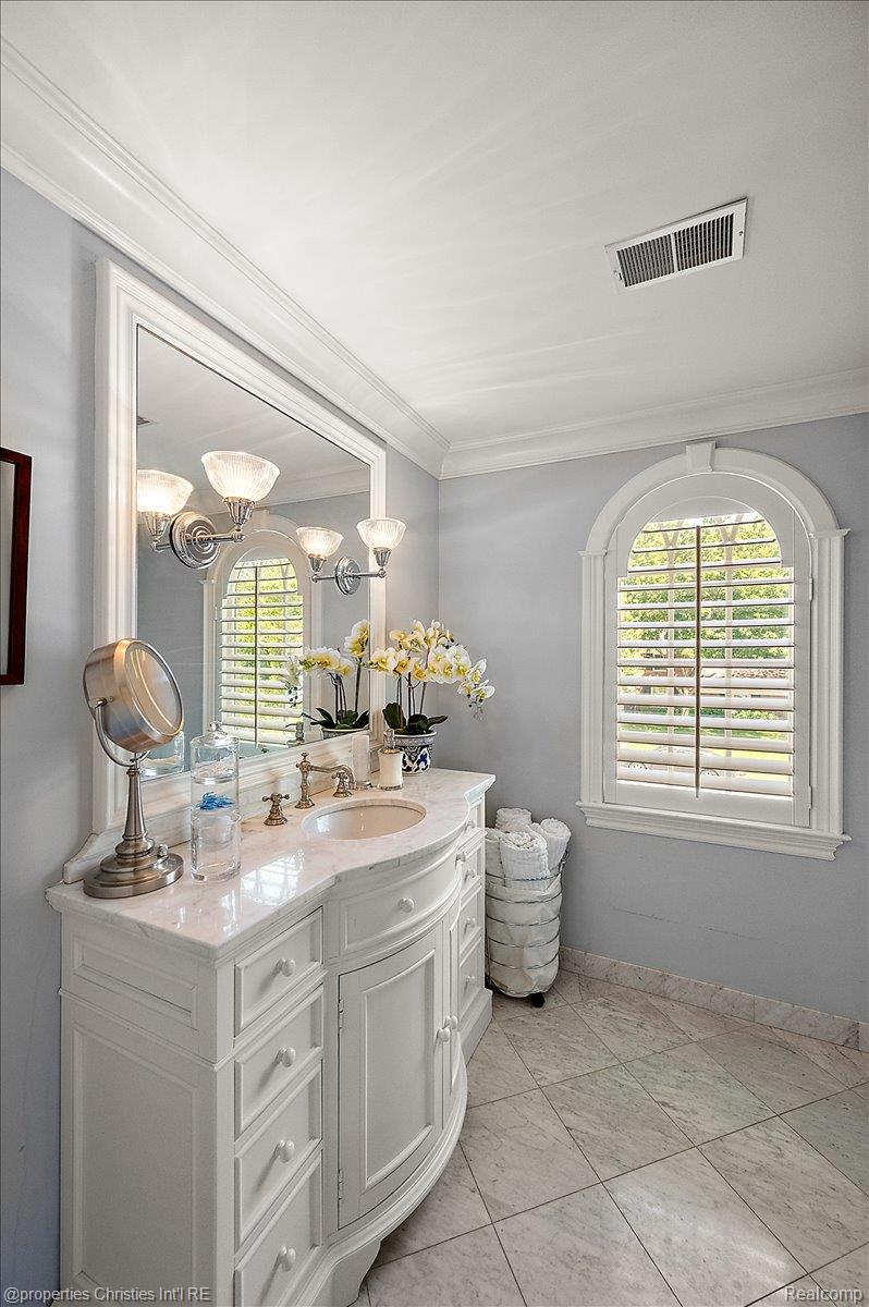 135 Clifton Road Bloomfield Hills, MI 48301 - Photo 54 of 77 White vanity with a marble countertop and integrated sink, complemented by a large framed mirror with sconce lighting