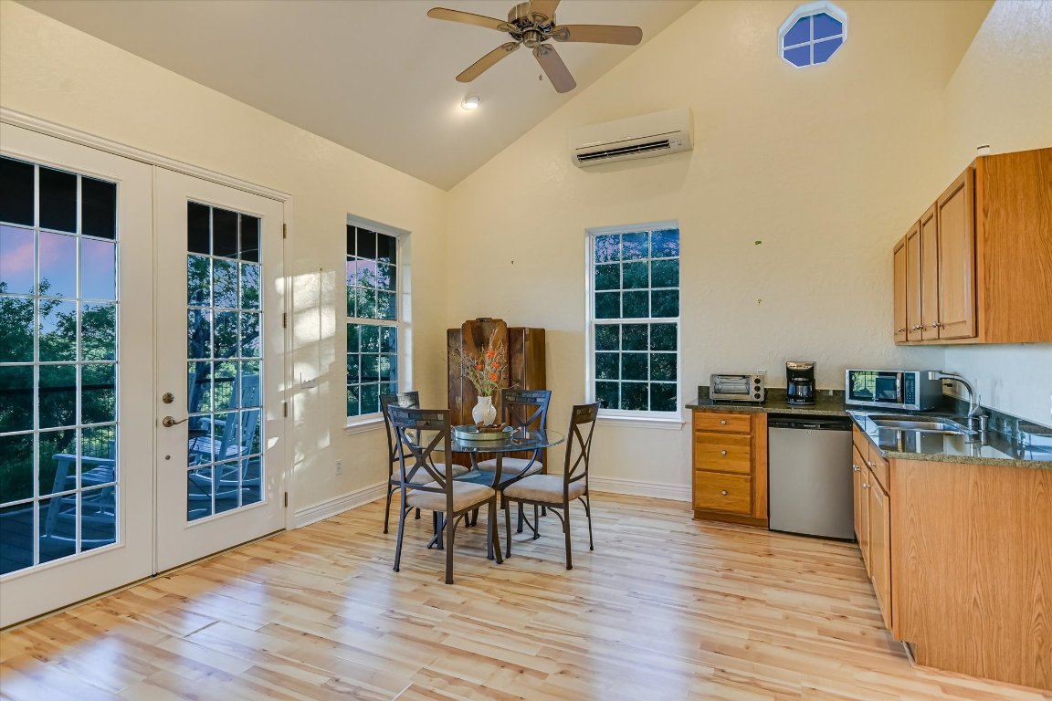 1050 River Mountain Road, Unit A Wimberley, TX 78676 - Photo 35 of 40 a kitchen with stainless steel appliances granite countertop a stove top oven a sink dishwasher and a dining table with wooden floor