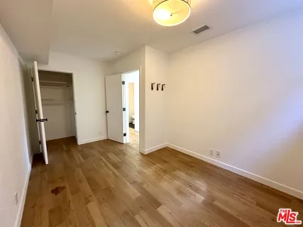 a view of an empty room with wooden floor and closet
