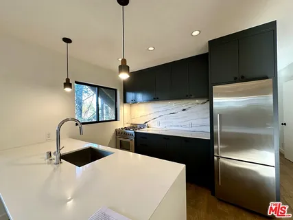 a kitchen with stainless steel appliances kitchen island a refrigerator sink and stove