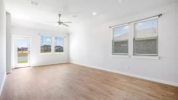 a view of an empty room with a window and wooden floor