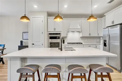 a kitchen with stainless steel appliances granite countertop a stove a sink a microwave a dining table and chairs with wooden floor