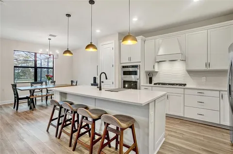 a kitchen with granite countertop a stove a sink and a dining table with wooden floor