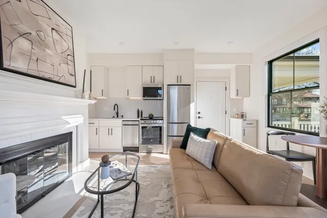 a living room with furniture a fireplace and kitchen view