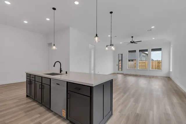 a kitchen with a sink chandelier and wooden floor
