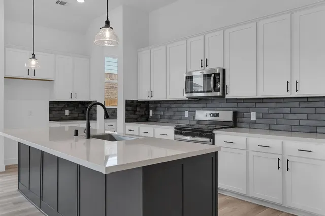 a kitchen with stainless steel appliances granite countertop a sink a stove and cabinets
