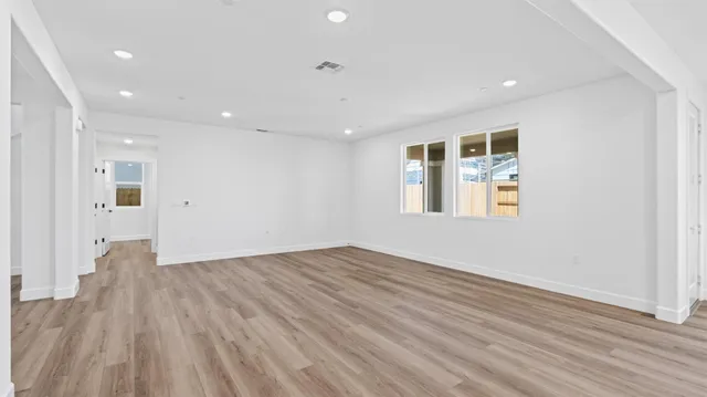 an empty room with wooden floor and windows