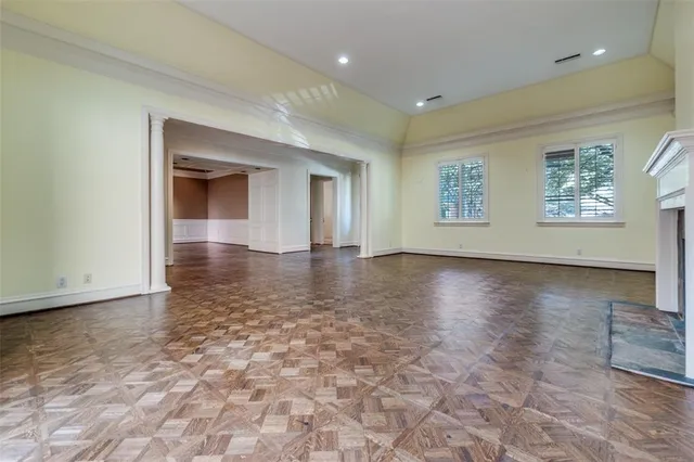 a view of an empty room with window and wooden floor