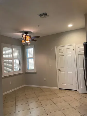 an empty room with chandelier fan and windows