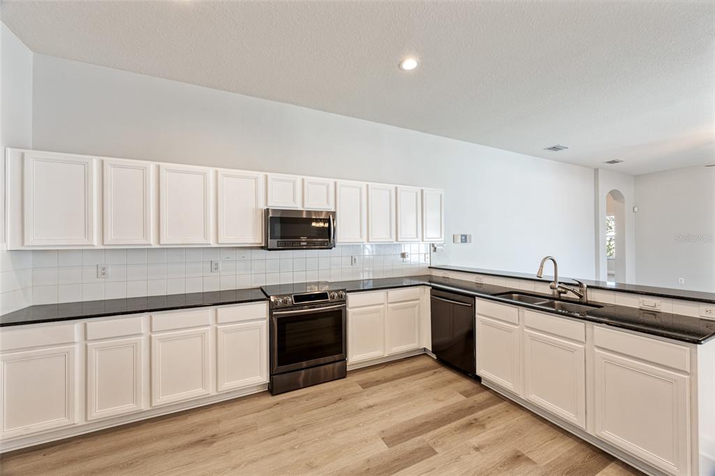 4925 Brightstone Place Spring Hill, FL 34609 - Photo 11 of 40 a kitchen with stainless steel appliances granite countertop a sink and cabinets