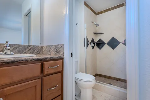 a bathroom with a granite countertop sink toilet and shower