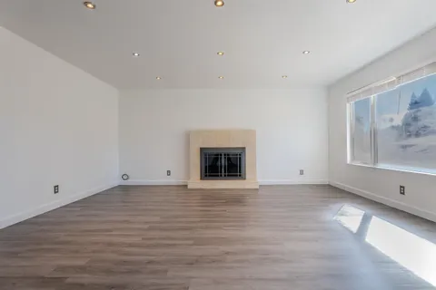 a view of an empty room with a window and fireplace